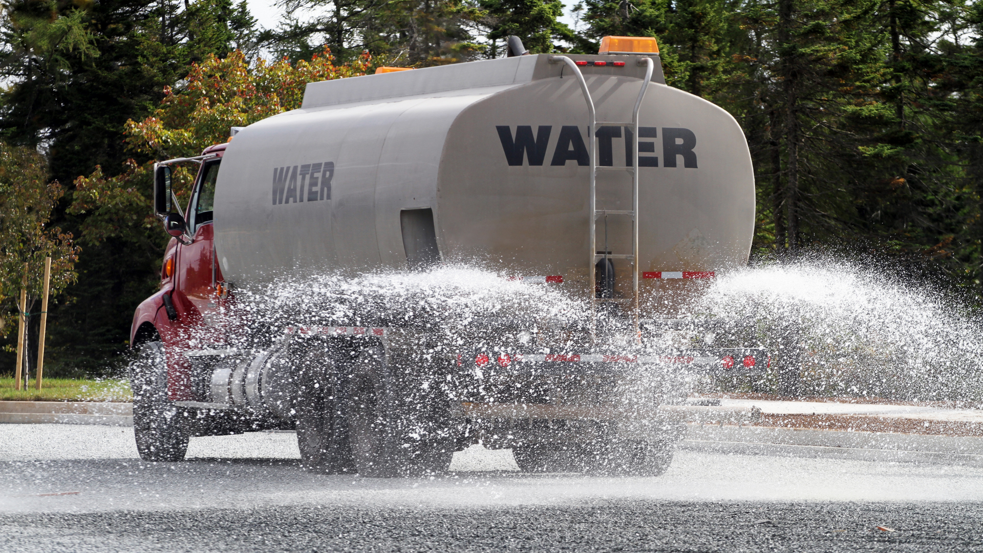 A water truck is driving through a puddle of water