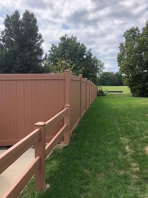 A wooden fence surrounds a lush green field.