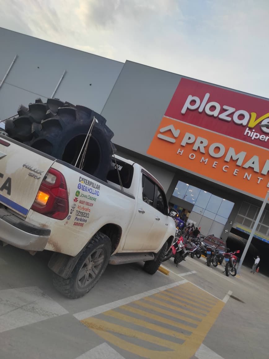 Camioneta Toyota blanca con llanta de gran tamaño estacionada en supermercado Plaza Vea.