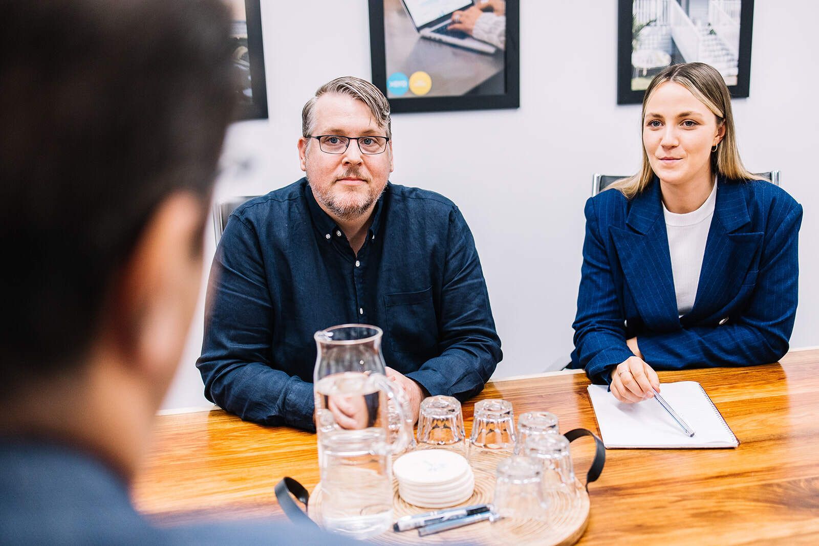 A Man And A Woman Are Sitting At A Table Having A Meeting — The Garis Group  In Hamilton, NSW 