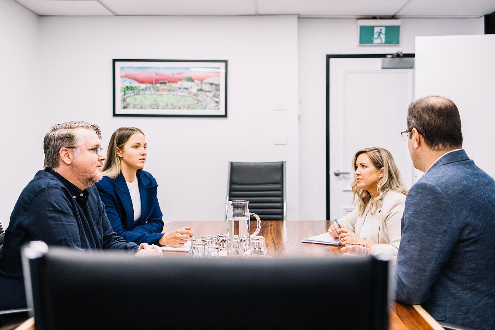 A Group Of People Are Sitting Around A Table In A Conference Room — The Garis Group  In Sydney, NSW