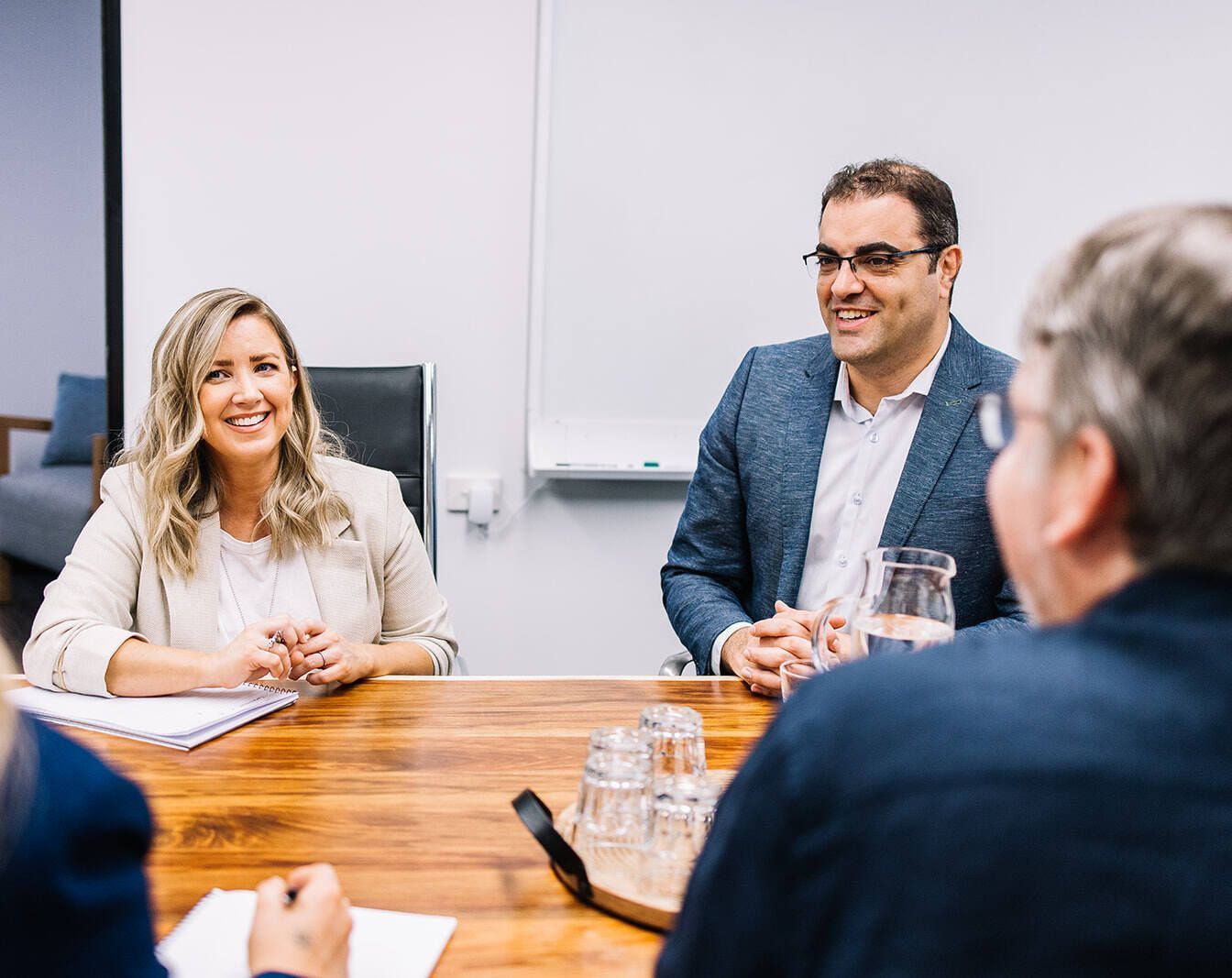 A Group Of People Are Sitting Around A Table Having A Meeting — The Garis Group  In Hamilton, NSW 