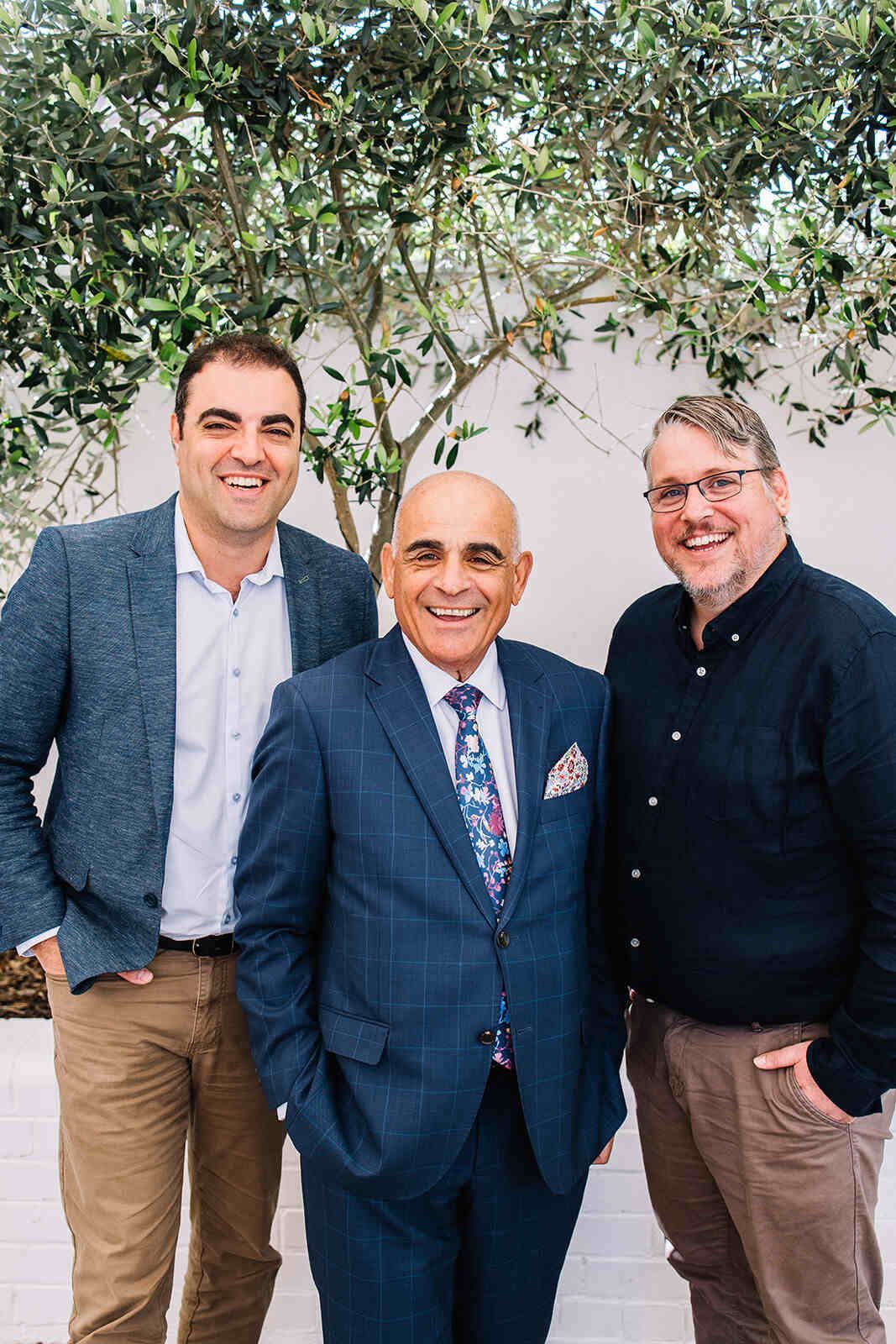 Three Men In Suits And Ties Are Posing For A Picture — The Garis Group  In Hamilton, NSW 