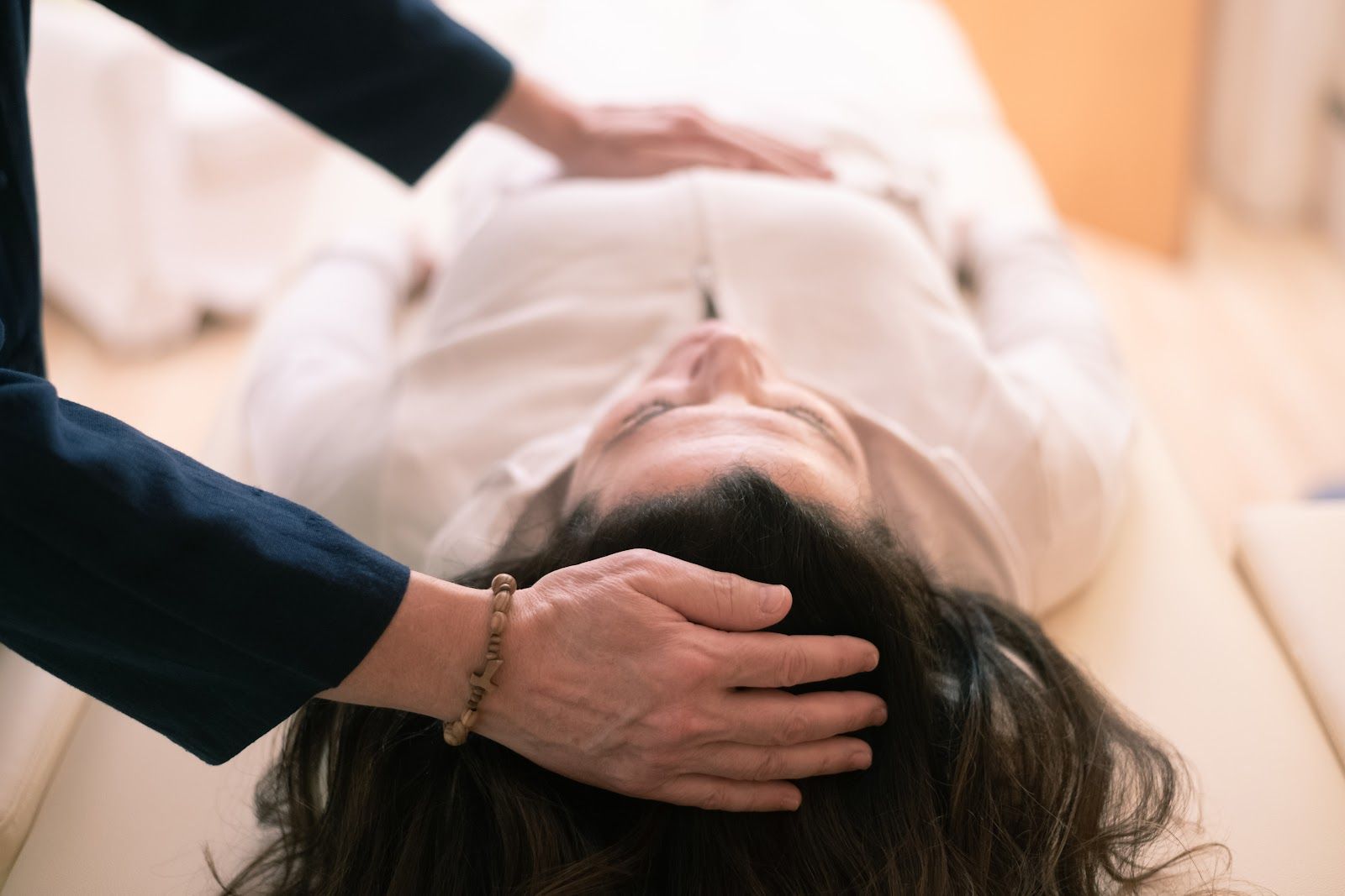 Hand resting on a person's head during a massage on a table