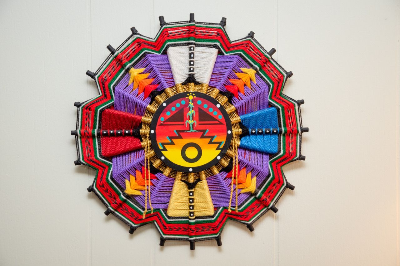 A colorful mandala is hanging on a white wall