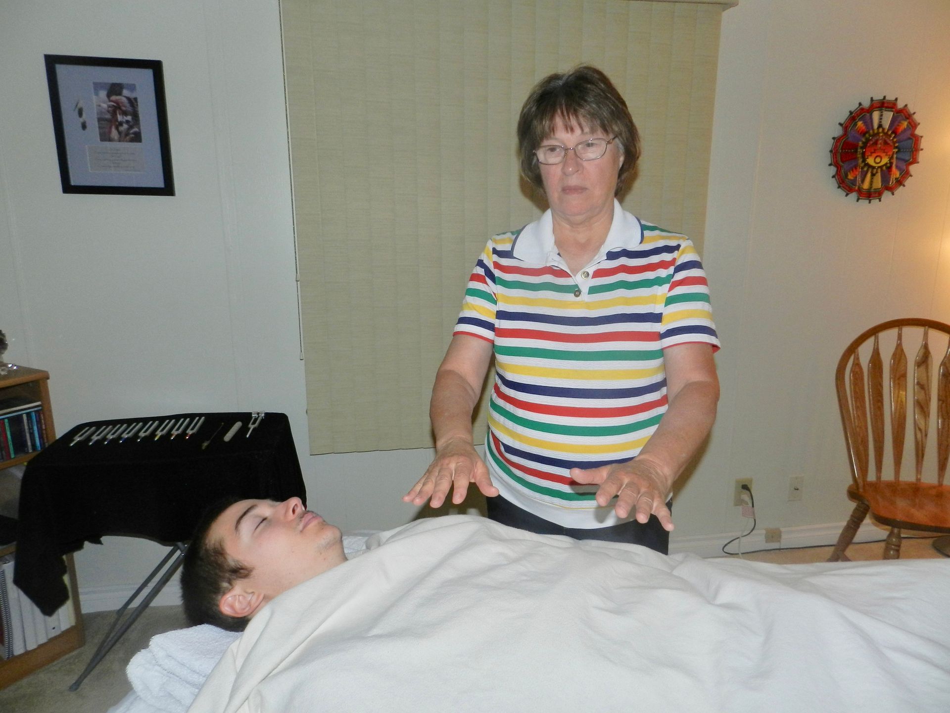 A woman in a striped shirt is giving a man a massage