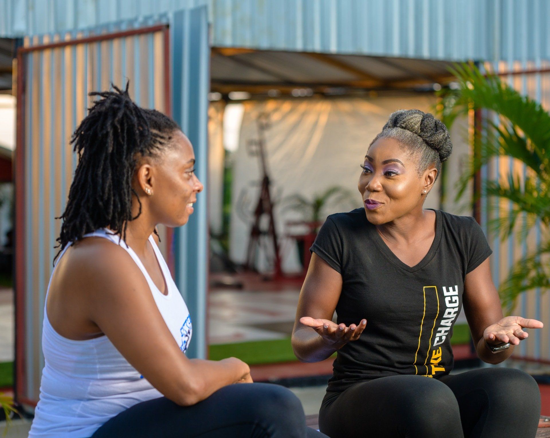 Two women are sitting on the ground talking to each other.