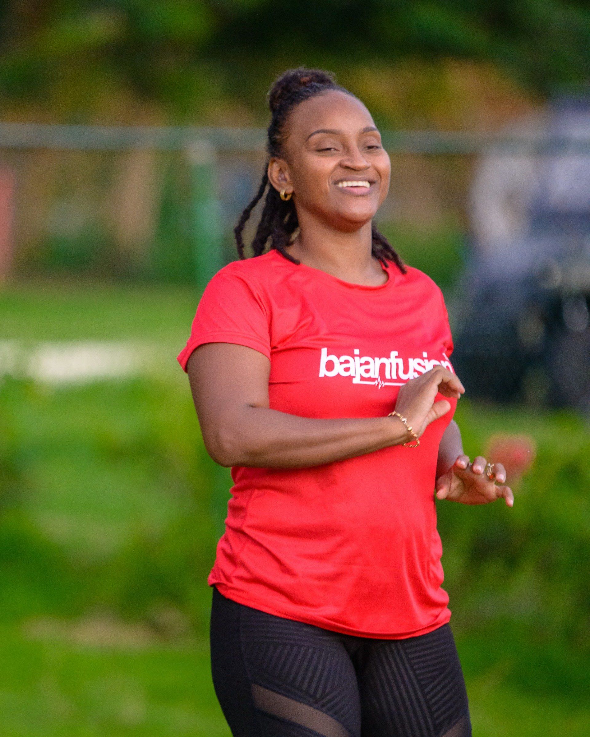 A woman in a red shirt is running in a park.