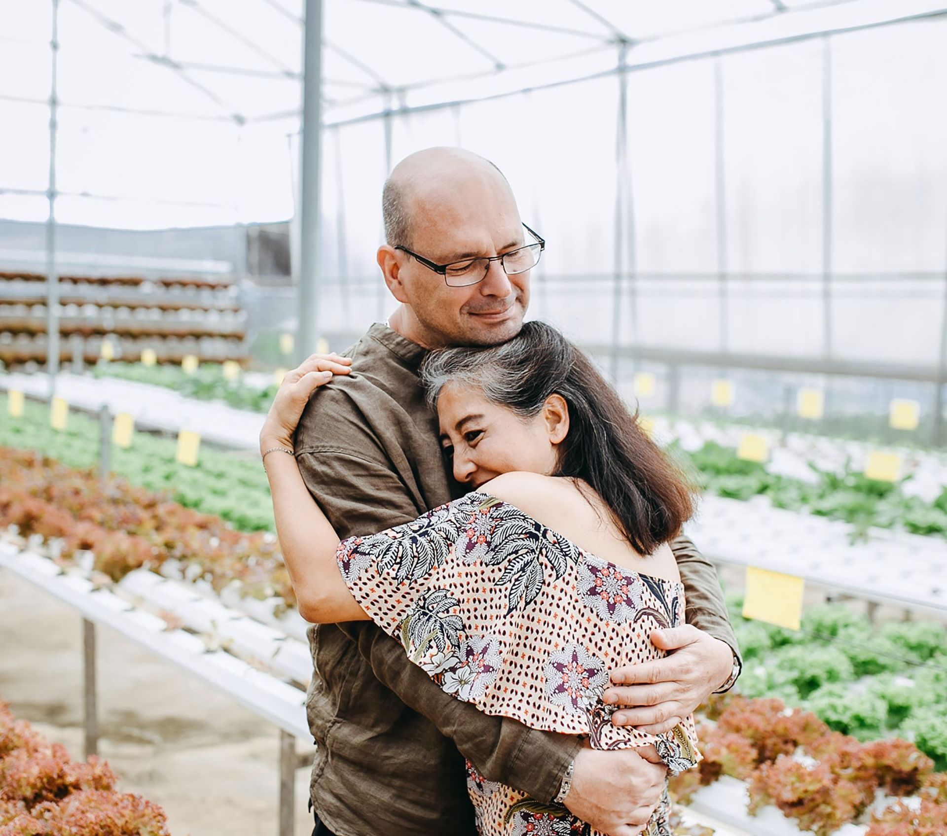 a man and a woman hugging in a greenhouse