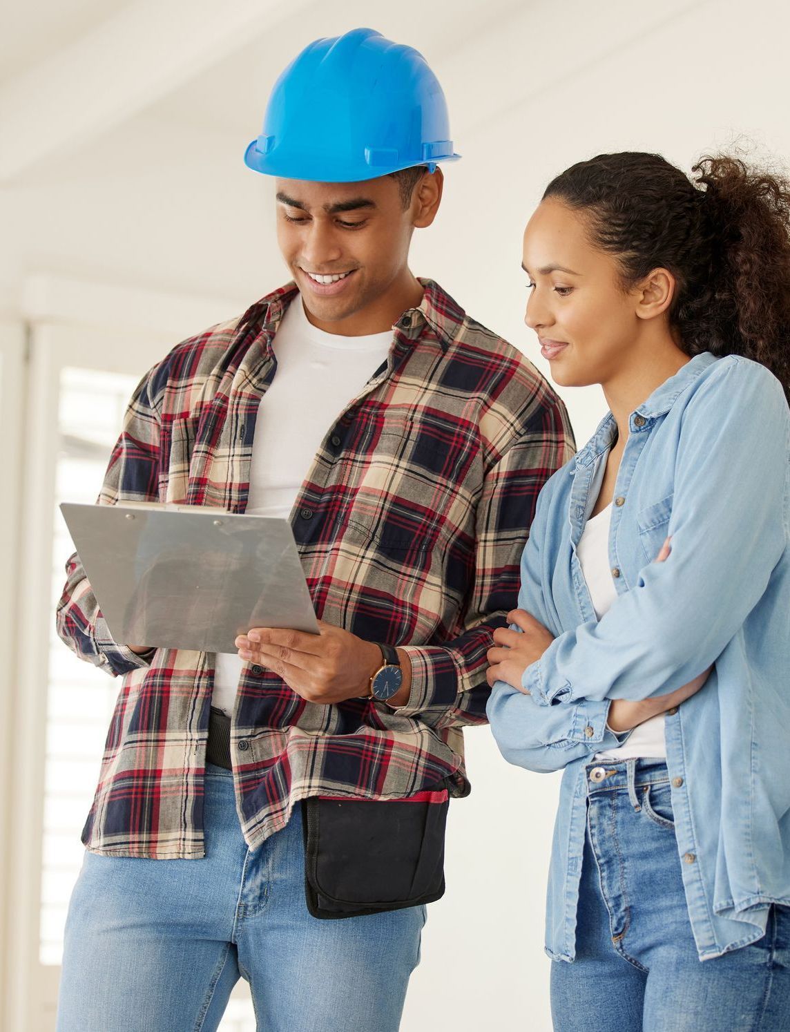 a man wearing a blue hard hat looks at a clipboard next to a woman