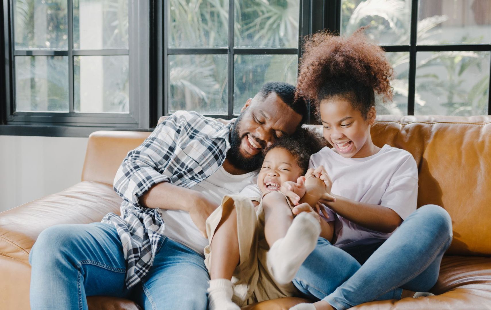 a man and two children are sitting on a couch and laughing