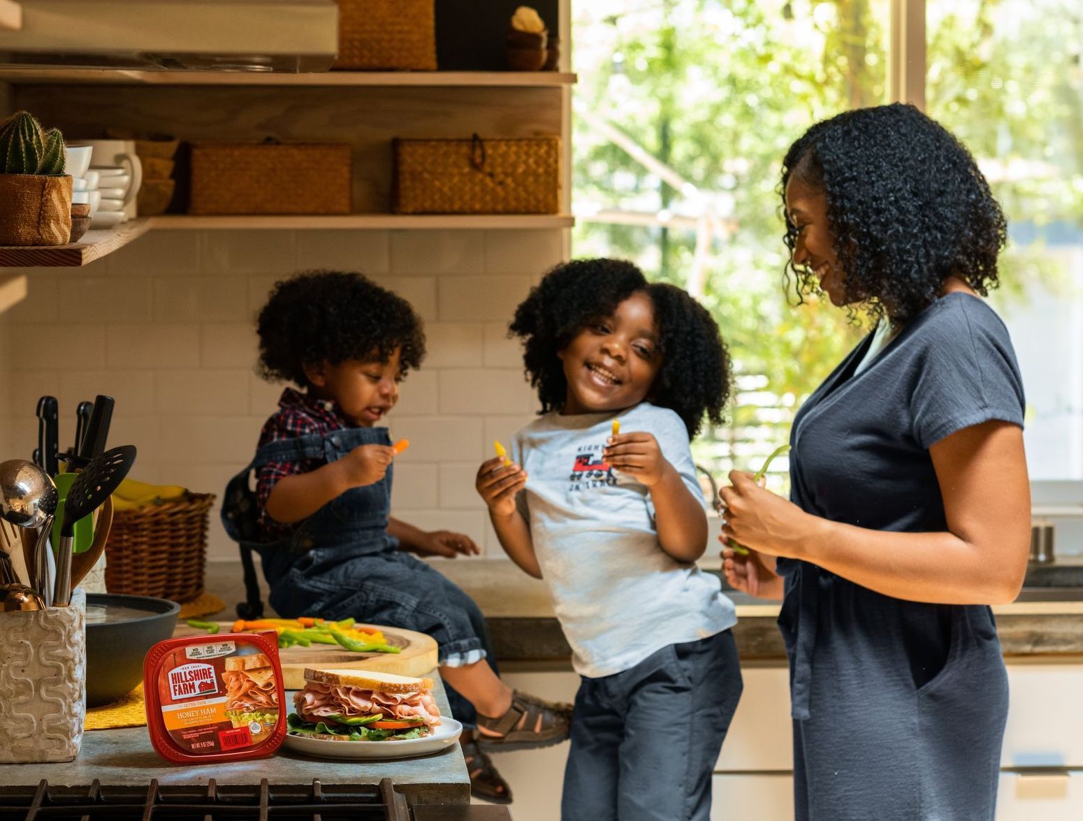 a woman and two children in a kitchen with a container of yellow ribbon ham