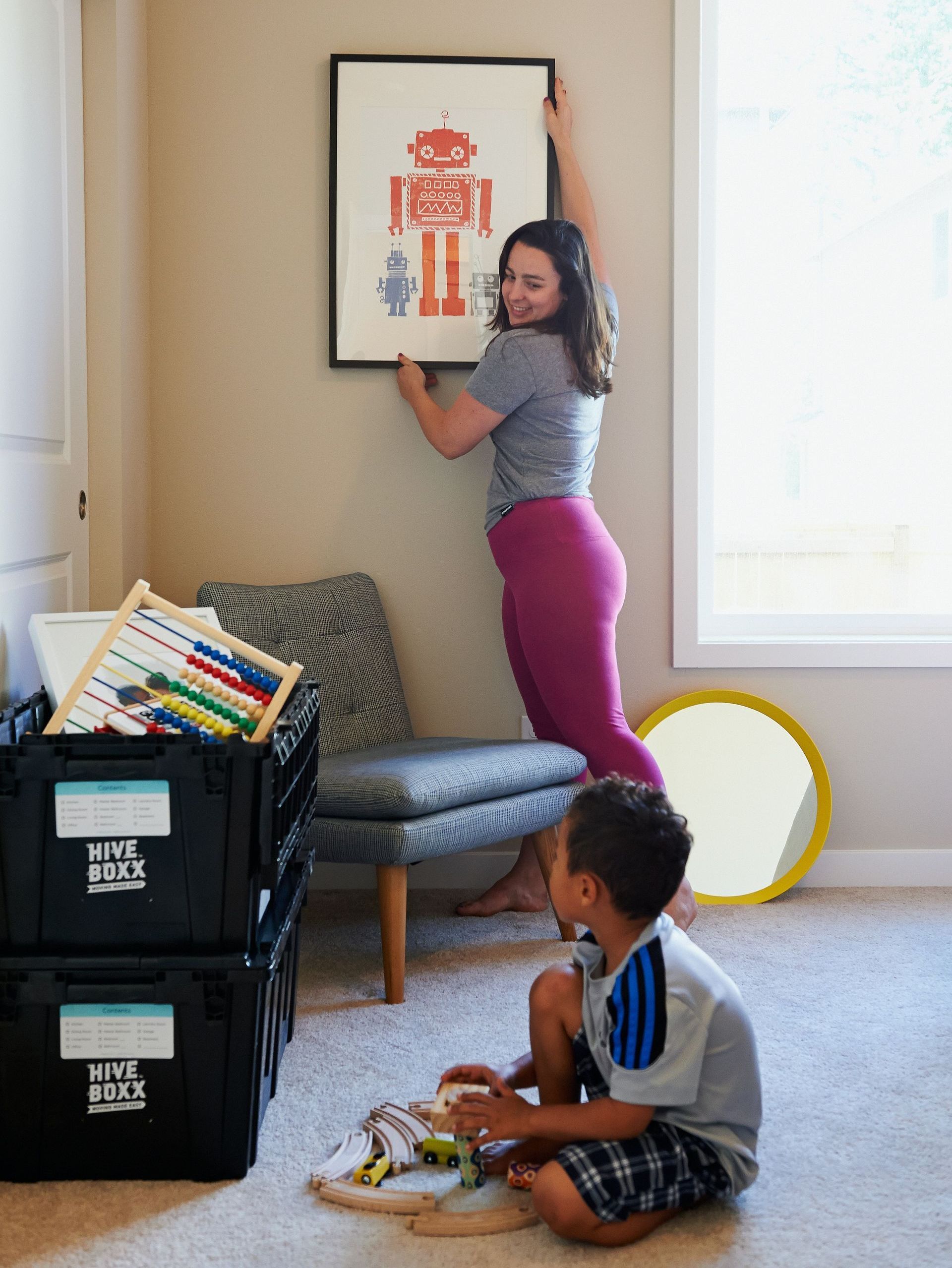 a woman hangs a picture of a robot on the wall