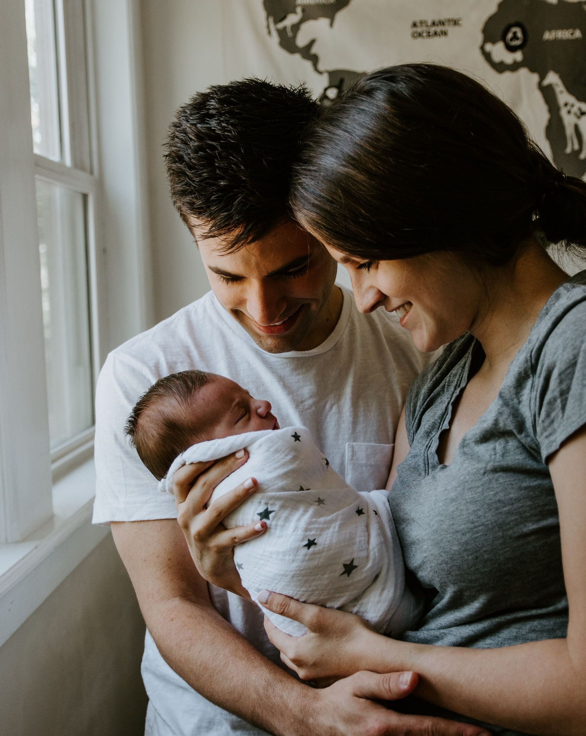 a man and woman holding a baby in front of a map of the atlantic ocean