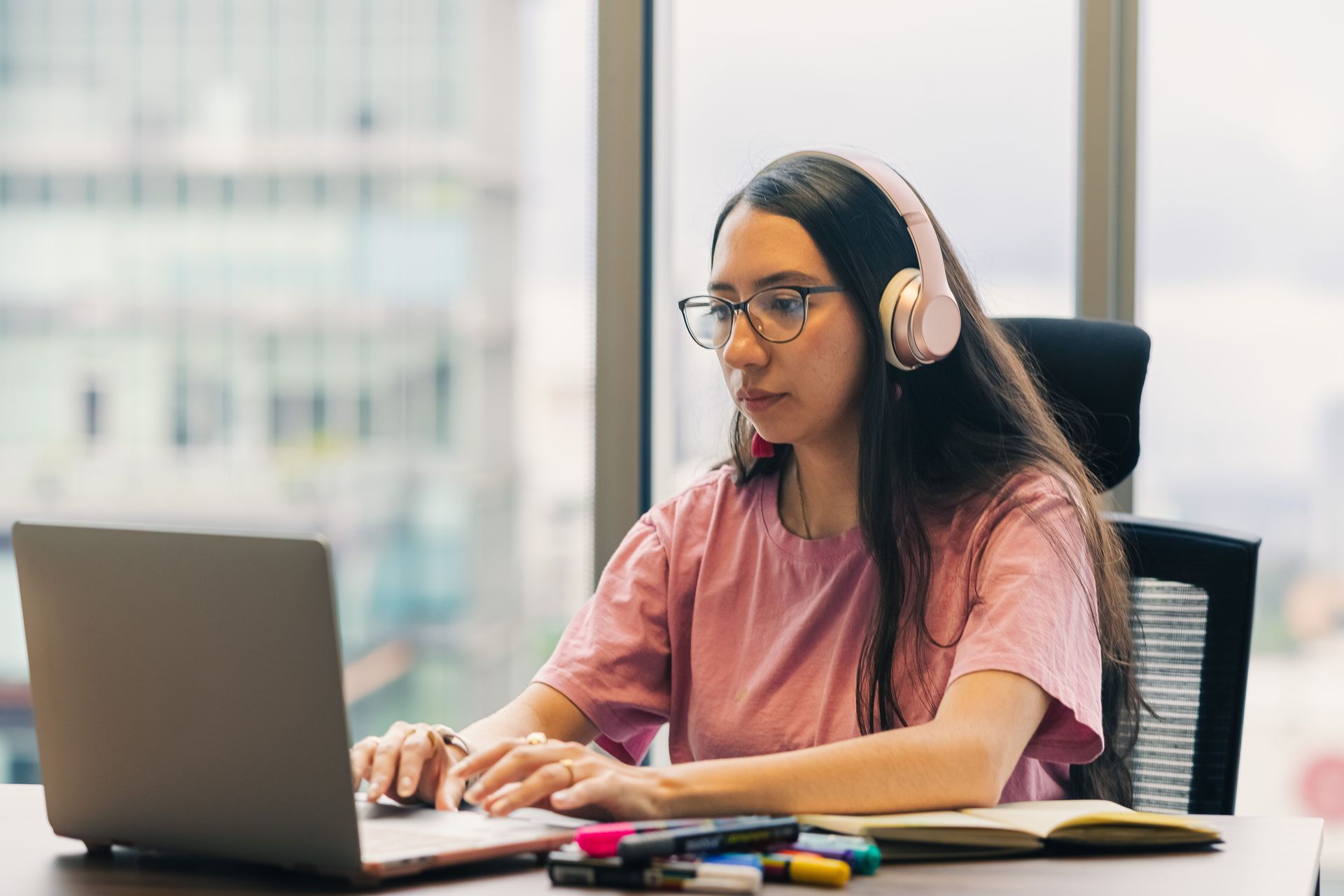 a professional woman in a pink shirt stands in front of a laptop