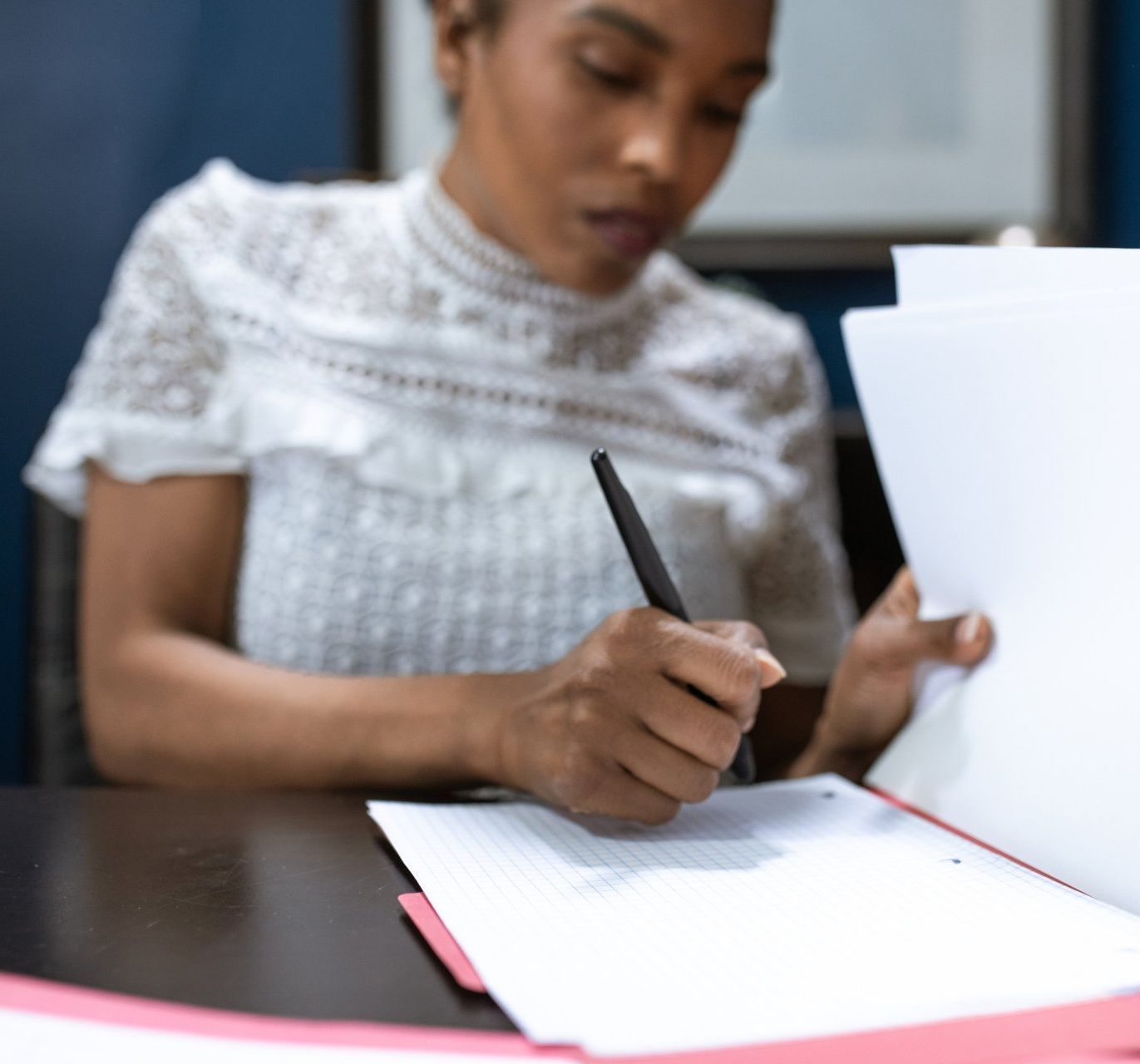 a woman is writing on a piece of paper with a pen