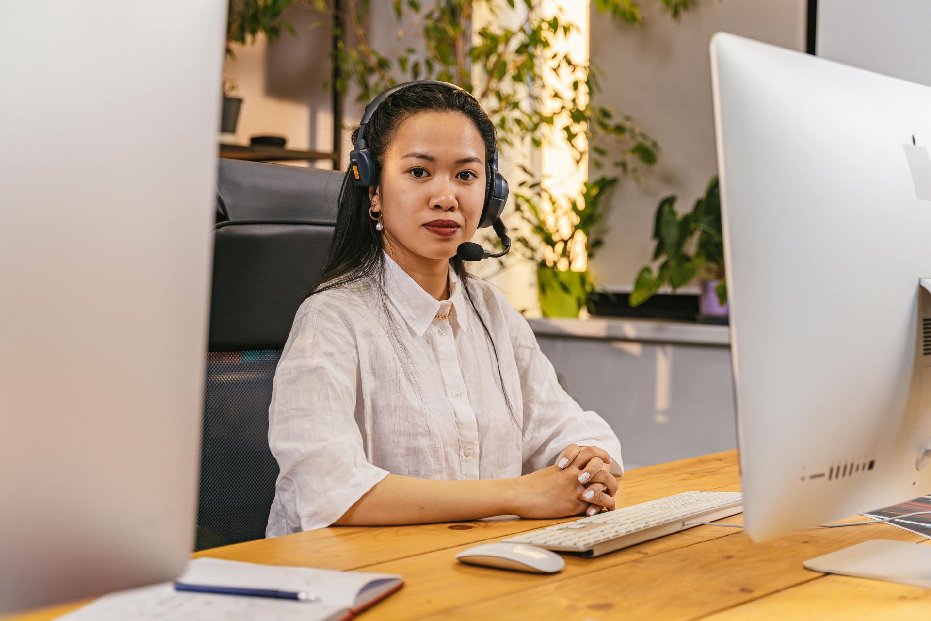 a professional woman in a pink shirt stands in front of a laptop