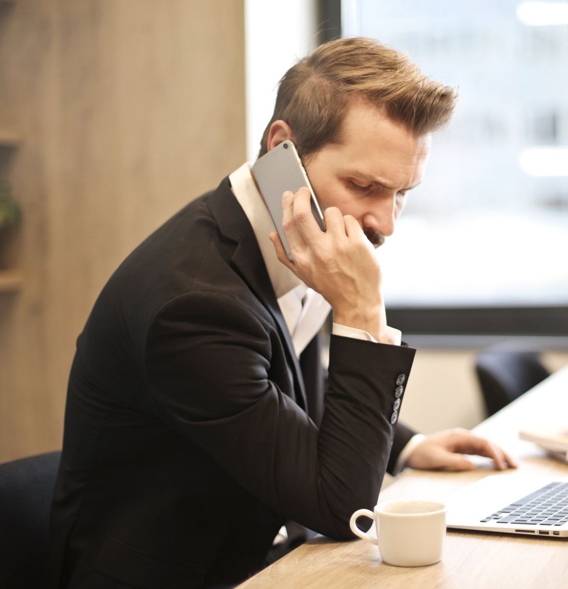 a man in a suit is talking on a cell phone