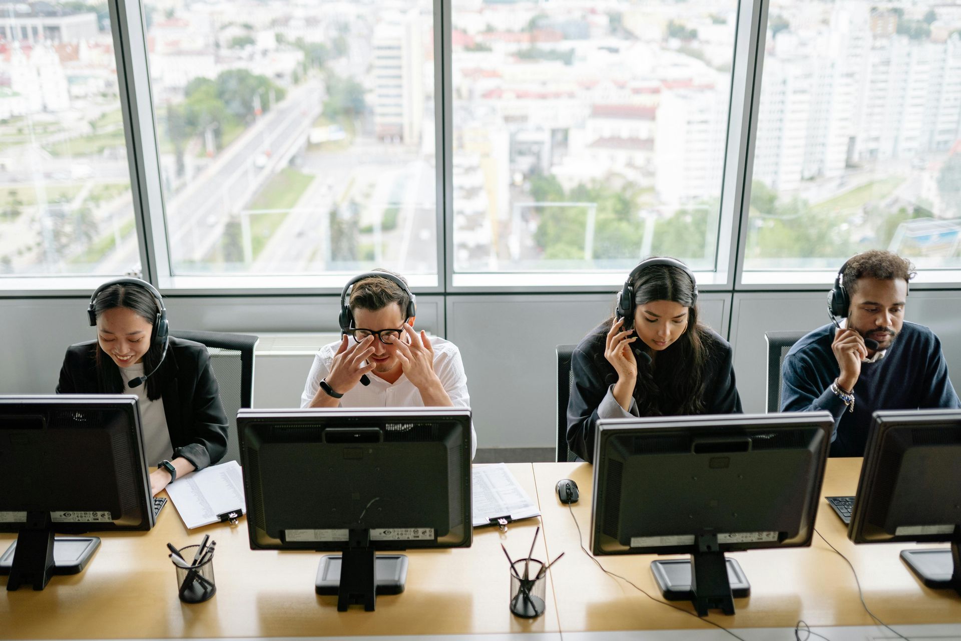 People with headsets at computers in an office, likely call center representatives.