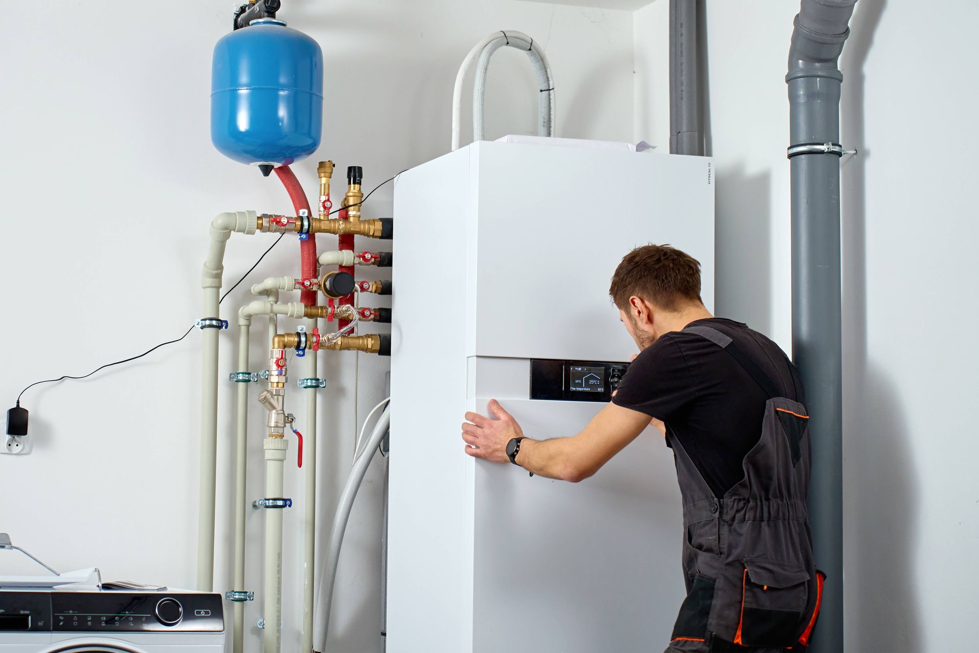 HVAC technician inspecting and adjusting residential boiler controls during routine maintenance.