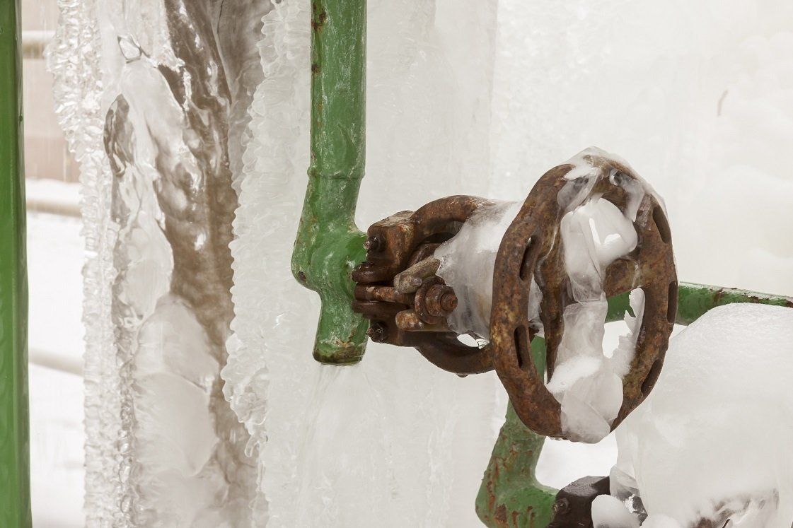 Green pipe and rusty valve encased in ice.