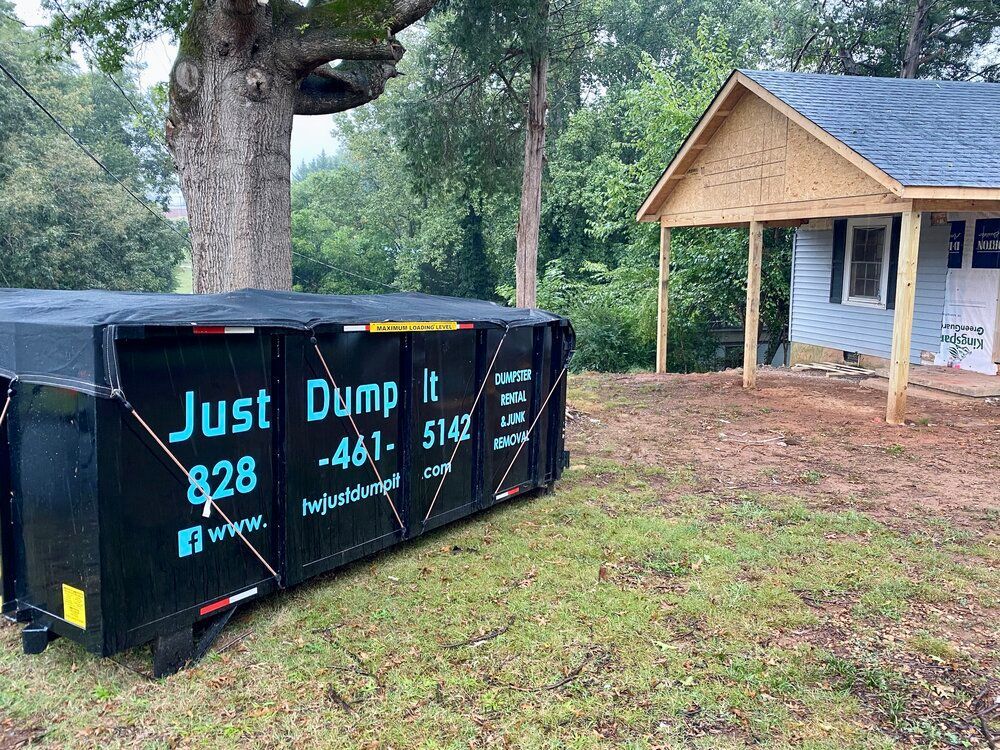 A dumpster is sitting in front of a house under construction.