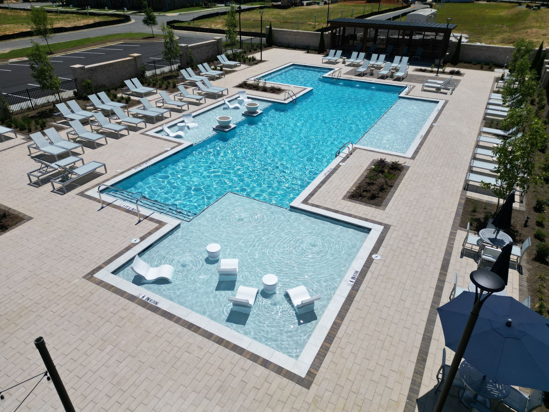 An aerial view of a large swimming pool surrounded by chairs and umbrellas.