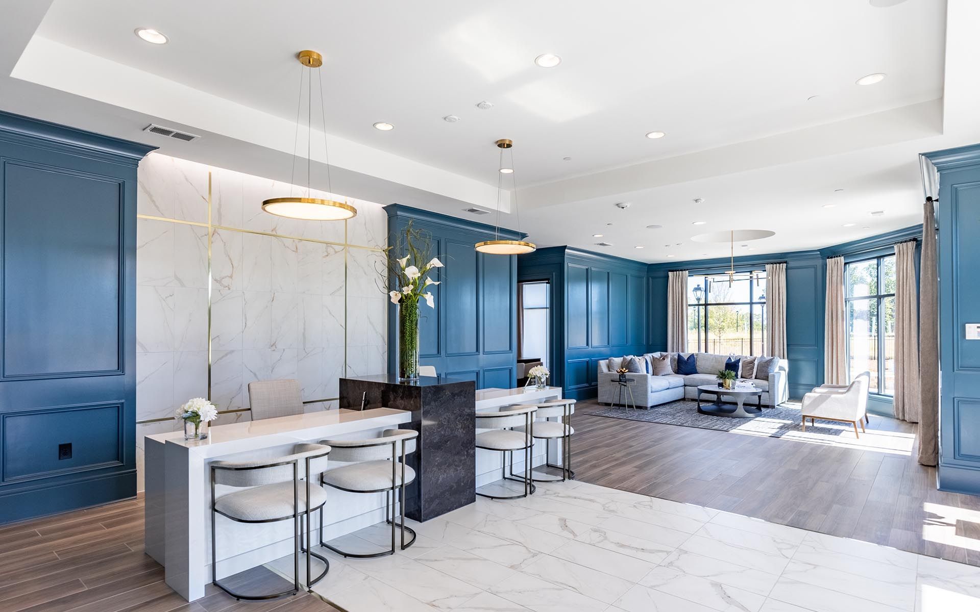 A large living room with blue walls , a bar , stools , and a couch.