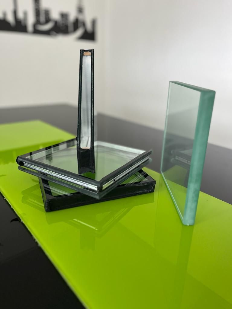 Dos muestras de vidrio sobre una mesa de color verde brillante, una en posición vertical y la otra sobre una base 
