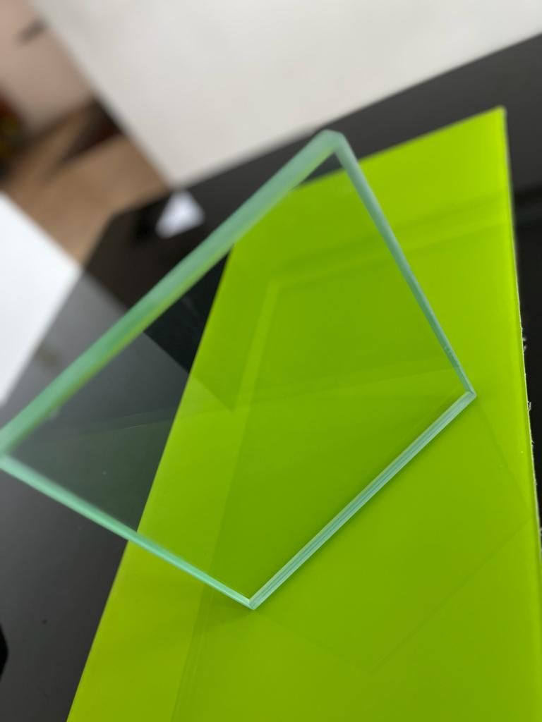 Un cuadrado de cristal sobre una superficie verde neón, colocado en ángulo.
