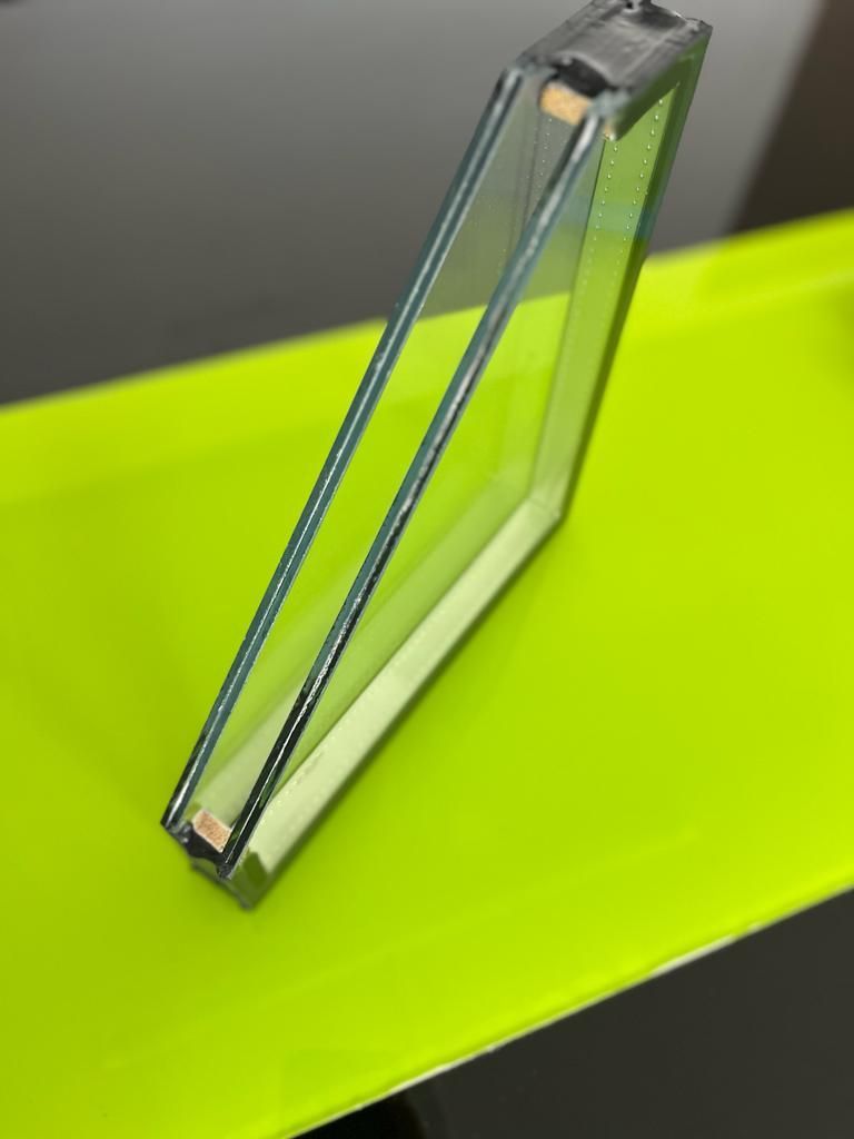 Un prisma triangular de vidrio transparente sobre una superficie de color verde lima brillante sobre un fondo gris.