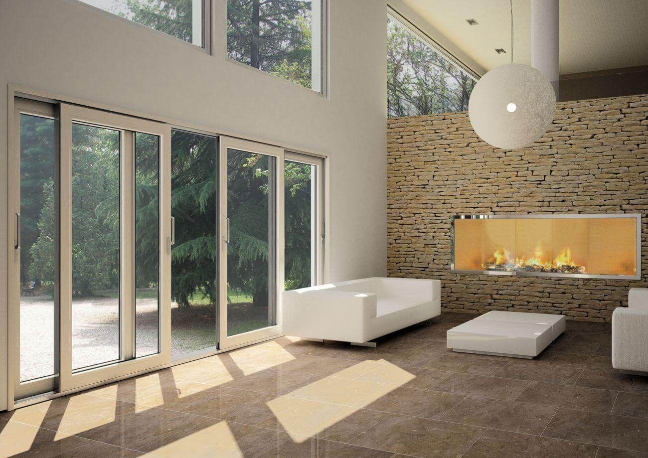 Salón moderno con ventanales del suelo al techo, chimenea de piedra y muebles minimalistas blancos.