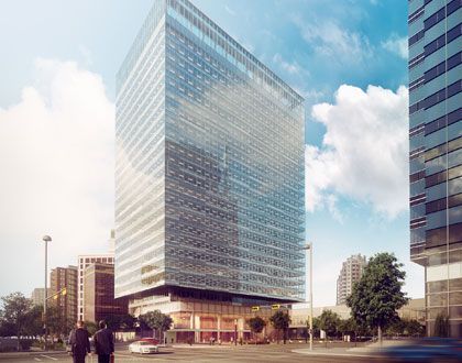Moderna torre de oficinas de cristal en una plaza de la ciudad con gente caminando debajo y árboles cerca.