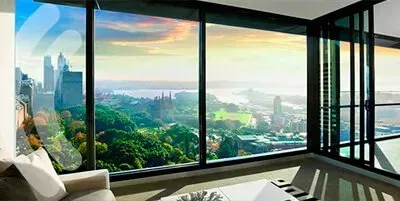 Moderna sala de estar con ventanales del suelo al techo con vistas a un exuberante paisaje urbano y al paseo marítimo