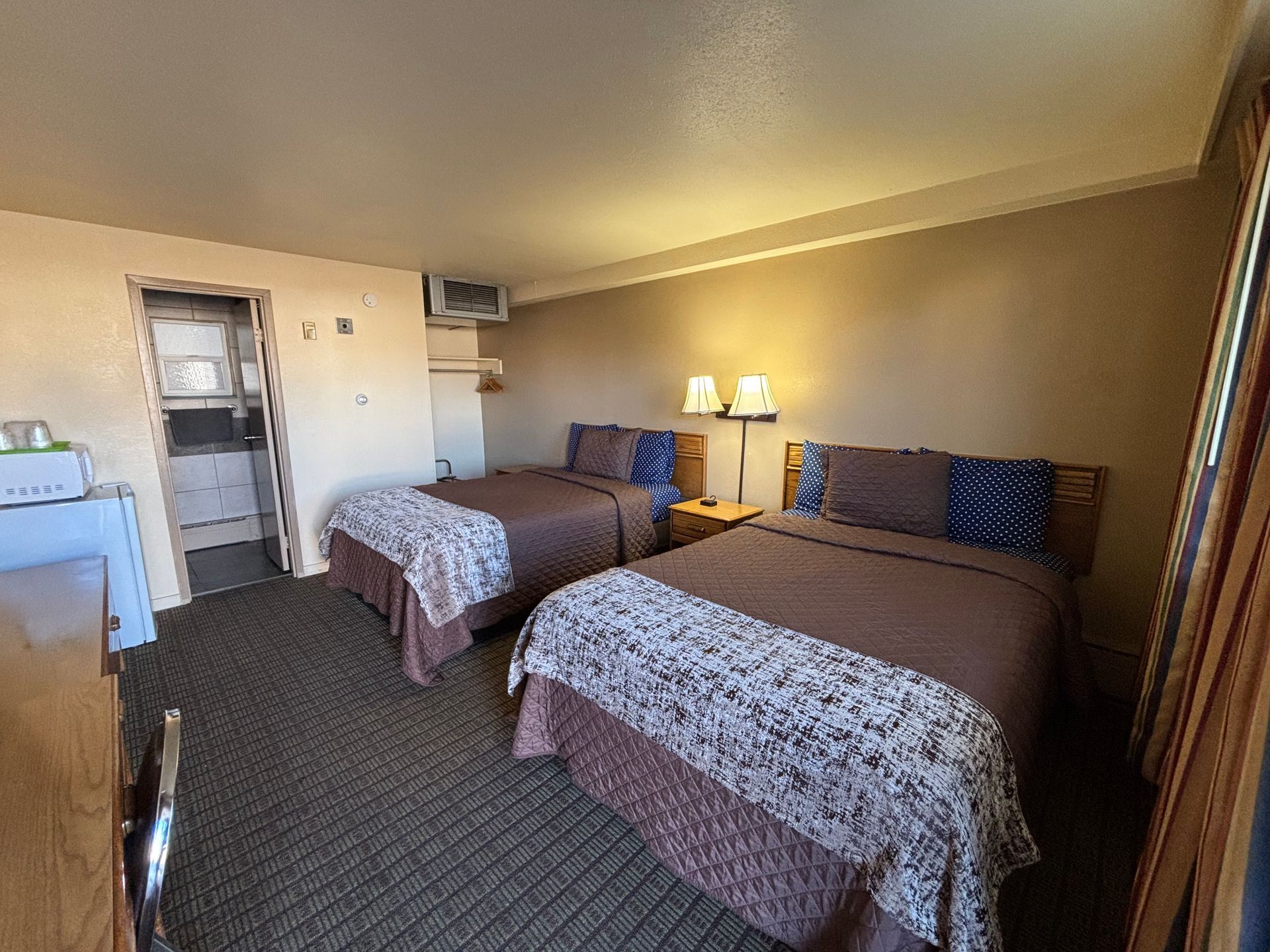 A hotel room with two beds and a microwave.