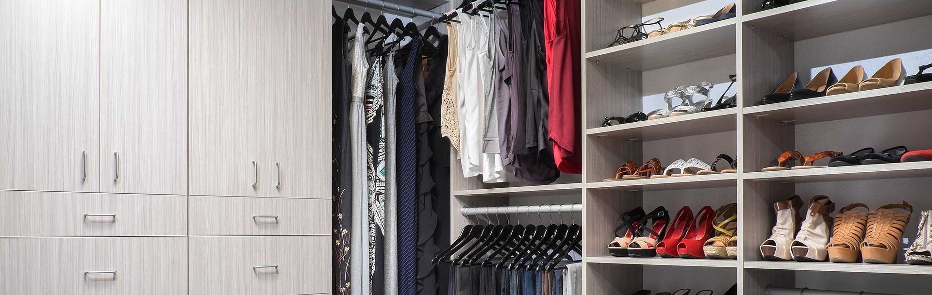 A walk in closet filled with lots of clothes and shoes.