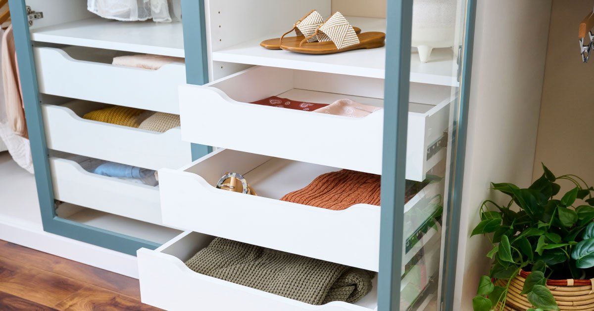 A closet with drawers and shelves filled with clothes and shoes.