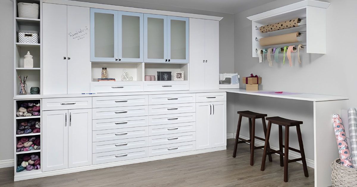 a craft room with a lot of white cabinets and stools .