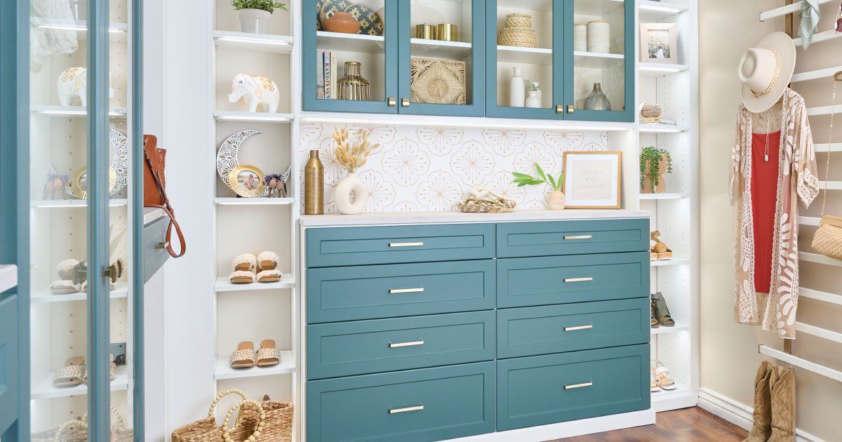 a walk in closet with lagoon cabinets and white shelves .