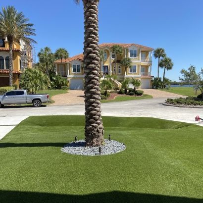 artificial grass around palm tree and planter with rocks