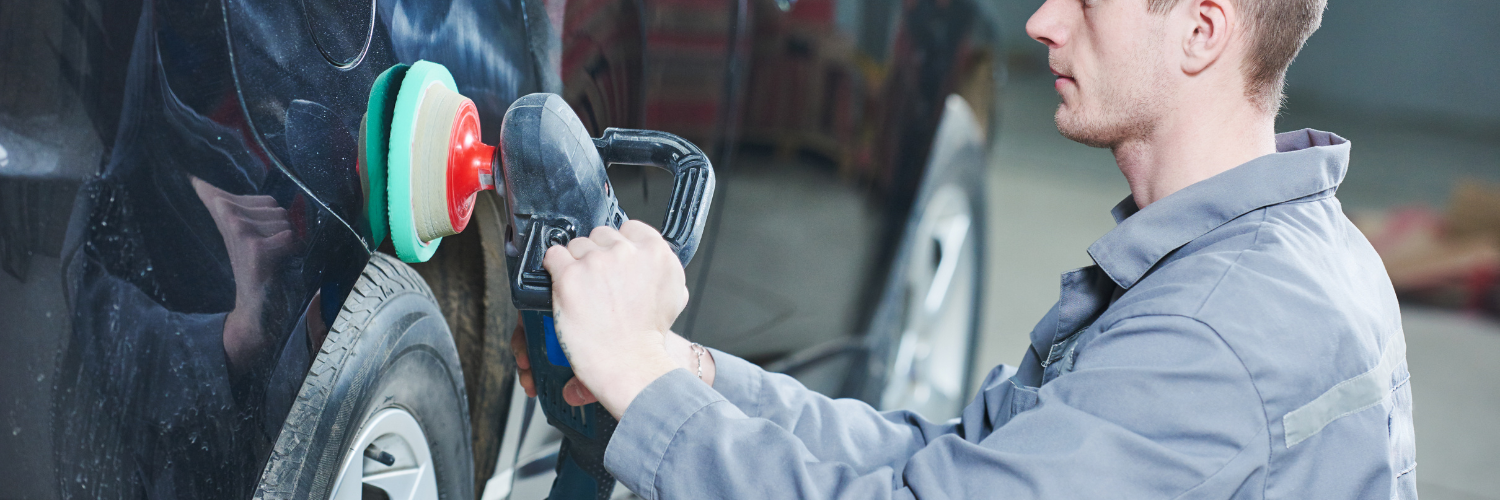 Mechanic polishing a car body with a buffer in an auto repair shop
