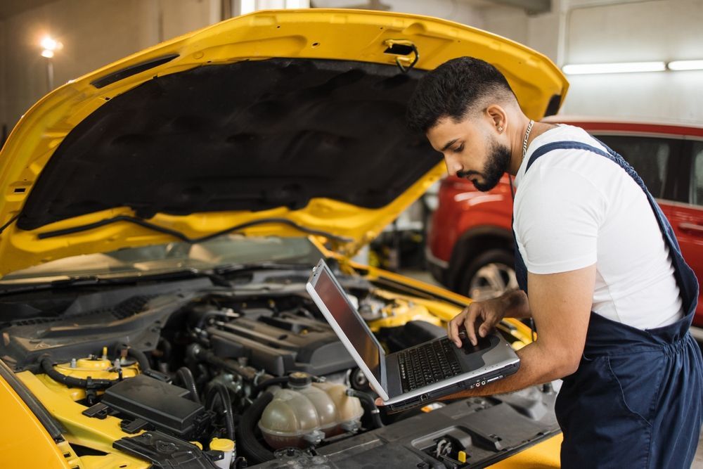 Mechanic Using a Laptop to Diagnose a Yellow Car — Hive Mobile Roadworthy in Burleigh Heads, QLD