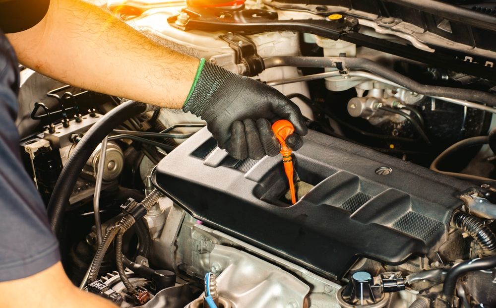 A Man is Checking the Oil Level of a Car Engine — Hive Mobile Roadworthy in Southport, QLD