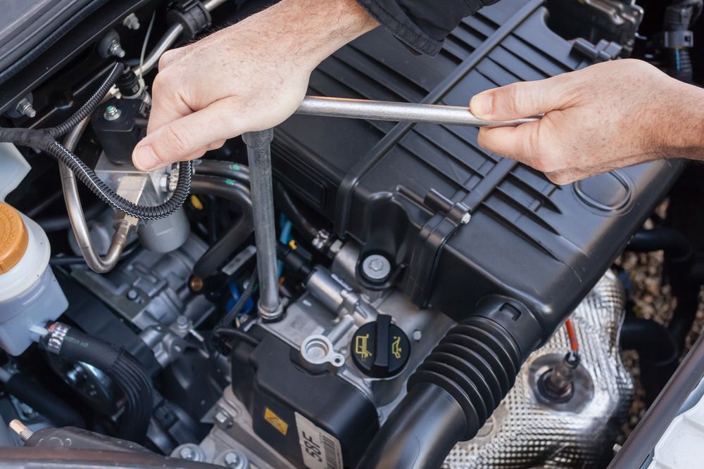 A Man is Working on the Engine of a Car With a Wrench — Hive Mobile Roadworthy in Currumbin, QLD