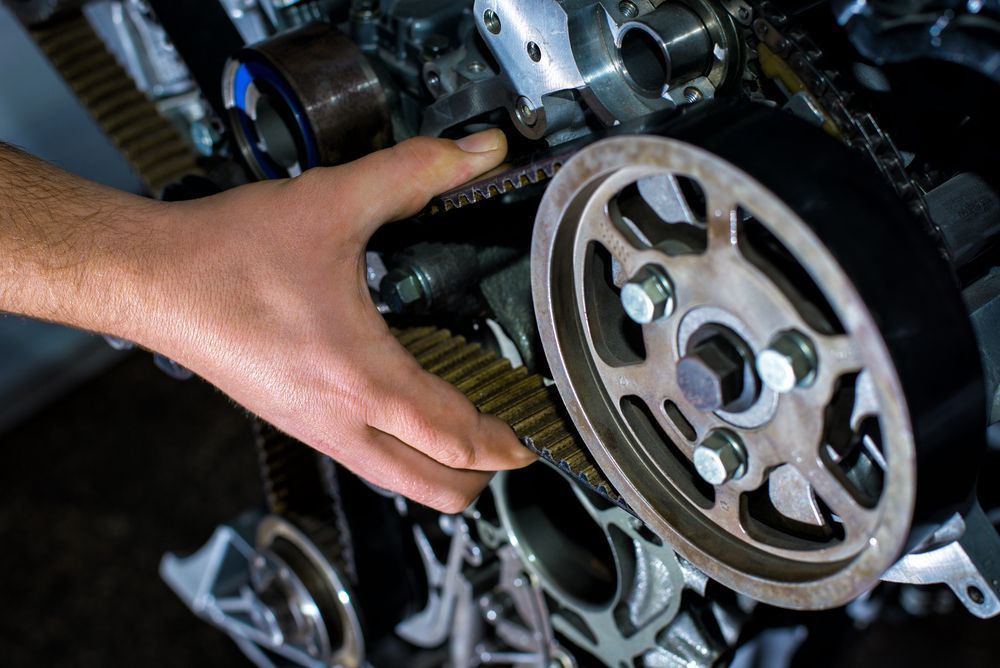 Hand Touching a Car Engine’s Timing Gear and Belt — Hive Mobile Roadworthy in Palm Beach, QLD