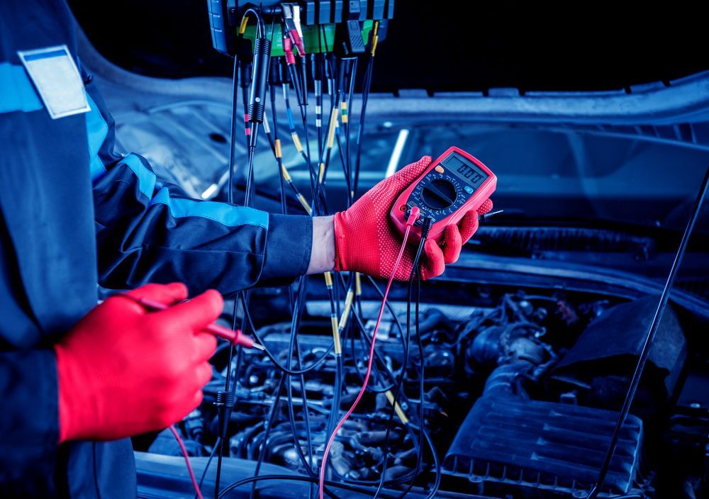 Mechanic in Red Gloves Using a Multimeter Under a Car Hood — Hive Mobile Roadworthy in Mudgeeraba, QLD