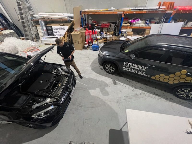 Person Working in a Garage Beside Two Black Cars — Hive Mobile Roadworthy in Coomera, QLD