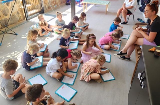 A woman is sitting in a chair reading a book to a group of children.