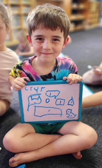 A little girl is holding up a drawing of a flower with numbers on it