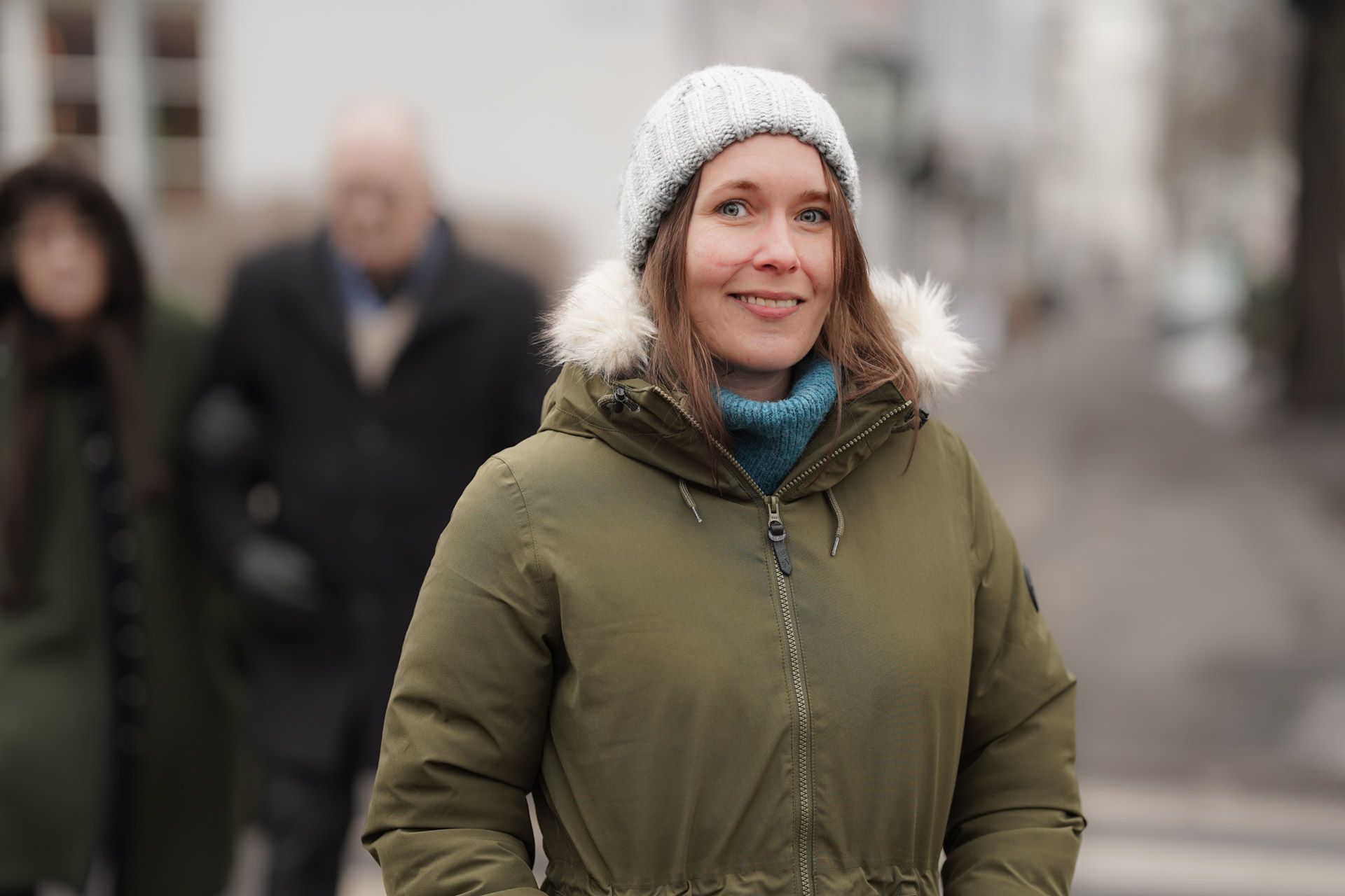 en kvinne i parkas og hatt går nedover gaten.
